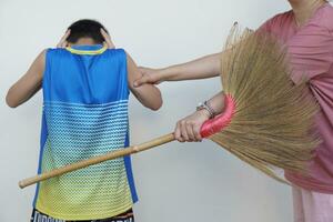 Close up woman holds broom to hit unidentified boy. Concept, campaign for stop punishing . Harsh punishment can be  cause of a child's aggressive behavior. Child rearing psychology photo