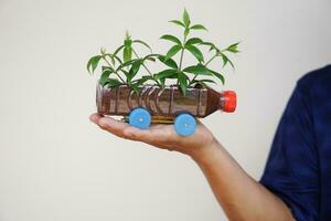 Close up hand hold DIY car which grow plants, made from plastic bottle and caps. Concept, Gardening from recycle crafts. Reduce, reuse and recycle plastic garbage photo