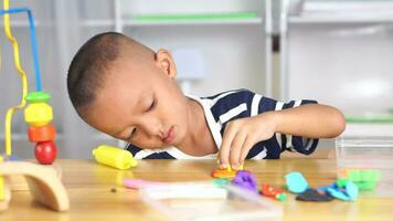 Boy making plasticine to promote development on the table in the house. video