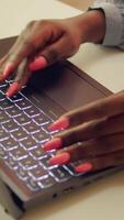 Vertical video Woman typing information on laptop, working to solve web project tasks at home. African american blogger writing story line for teleworking job, self employed developer. Close up.