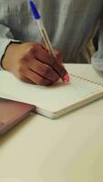 vertical vídeo blogger escritura historia ideas en cuaderno y creando plan para trabajo prioridades, desarrollando en línea carrera con Lanza libre trabajo a hogar. mujer tomando notas y comenzando a resolver Tareas video