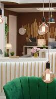 Vertical video Front desk hotel reception lobby, used to check in and welcome guests on holiday. Fashionable empty modern resort lounge area with expensive green furniture and classy decorations.