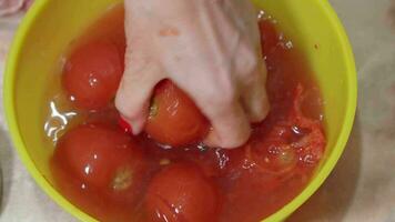 Woman crushes tomatoes to extract juice to make sauce at home. video