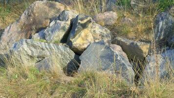 grande granito piedras de varios formas acostado a pie de montaña. video