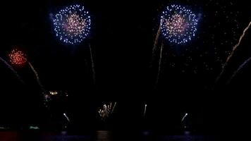 verbazingwekkend mooi kleurrijk vuurwerk Scherm over- zee Aan viering nacht. vuurwerk tonen voor gelukkig nieuw jaar, 4k beeldmateriaal video