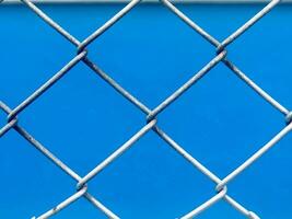 a blue background with a chain link fence photo