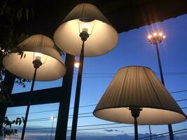 three lamps with white shades on top of a building photo