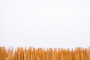 Toothpicks arranged in a long line in a white scene photo