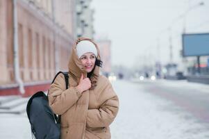 A cute girl in a coat and hat walks around the city in bad cold weather photo