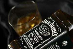 KYIV, UKRAINE - MAY 4, 2022 Jack Daniels original alcohol bottle on wooden table with black fabric photo