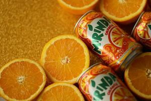 KYIV, UKRAINE - JULY 7, 2023 Mirinda orange drink with many oranges on colorful background photo