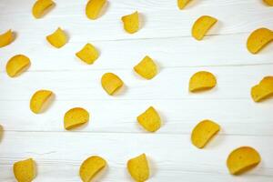 Many orange Pringles potato snack chips on white wooden table. Pringles is a brand of potato snack chips owned by Kellogg Company photo