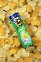 Pringles sour cream onion flavour. Cardboard tube can on many Pringles potato chips background. Pringles is a brand of potato snack chips owned by Kellogg Company photo