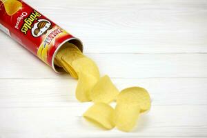 Pringles original flavour. Cardboard tube can with Pringles potato chips on white table. Pringles is a brand of potato snack chips owned by the Kellogg Company photo