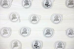 Pringles logo on paper membranes on white wooden table. Pringles is a brand of potato snack chips owned by Kellogg Company photo