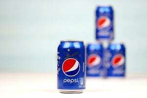 KHARKOV, UKRAINE - DECEMBER 8, 2020 Aluminium cans of Pepsi soft drink on white wooden table. Pepsi is carbonated soft drink produced by PepsiCo was created and developed in 1893 photo