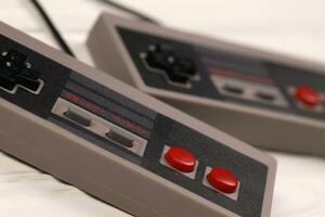 KHARKOV, UKRAINE - DECEMBER 27, 2020 Two old gamepads for 8-bit video game consoles nintendo entertainment system and nes mini on white table. Old school retro gaming photo