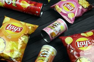 KHARKOV, UKRAINE - JANUARY 3, 2021 Various flavoured of lay's and pringles potato chips in classic packages design. Worldwide famous brands of potato chips photo