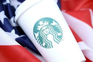 Jarkov, Ucrania - marzo 15, 2021 Starbucks taza en nosotros bandera. Starbucks sociedad es multinacional cadena de cafeterias con sede en Seattle, Washington foto