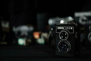 KHARKOV, UKRAINE - APRIL 27, 2021 Lubitel 166b and 2 Film photo camera and another old retro photo equipment on black wooden table in photographer darkroom. Photographic gear from soviet union