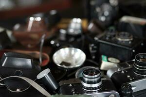 KHARKOV, UKRAINE - APRIL 27, 2021 Film photo cameras and another old retro photo equipment on black wooden table in photographer darkroom. Photographic gear from soviet union