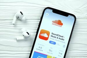 KHARKOV, UKRAINE - MARCH 5, 2021 Soundcloud icon and application from App store on iPhone 12 pro display screen with airpods pro on white table photo