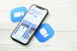 KHARKOV, UKRAINE - MARCH 5, 2021 Zoom messenger icon and application from App store on iPhone 12 pro display screen on white table photo