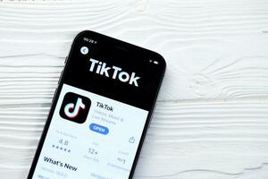 KHARKOV, UKRAINE - MARCH 5, 2021 Tiktok icon and application from App store on iPhone 12 pro display screen on white table photo