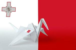 Malta flag depicted on paper origami crane wing. Handmade arts concept photo