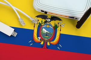 Ecuador flag depicted on table with internet rj45 cable, wireless usb wifi adapter and router. Internet connection concept photo