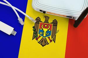 Moldova flag depicted on table with internet rj45 cable, wireless usb wifi adapter and router. Internet connection concept photo