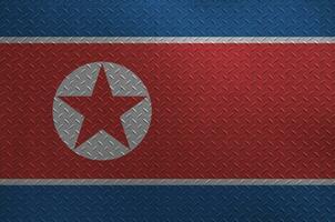 North Korea flag depicted in paint colors on old brushed metal plate or wall closeup. Textured banner on rough background photo