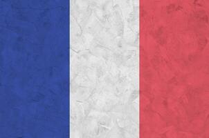 France flag depicted in bright paint colors on old relief plastering wall. Textured banner on rough background photo