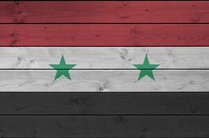 Siria bandera representado en brillante pintar colores en antiguo de madera pared. texturizado bandera en áspero antecedentes foto