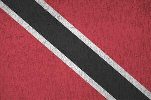 Trinidad and Tobago flag depicted in bright paint colors on old relief plastering wall. Textured banner on rough background photo