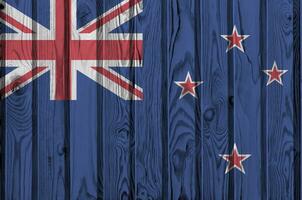 nuevo Zelanda bandera representado en brillante pintar colores en antiguo de madera pared. texturizado bandera en áspero antecedentes foto