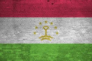 Tajikistan flag depicted in paint colors on old brick wall. Textured banner on big brick wall masonry background photo