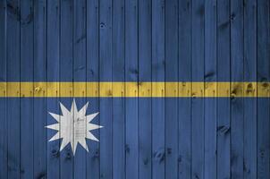 Nauru flag depicted in bright paint colors on old wooden wall. Textured banner on rough background photo