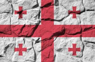 Georgia flag depicted in paint colors on old stone wall closeup. Textured banner on rock wall background photo