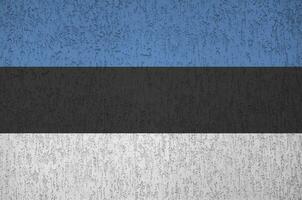 Estonia flag depicted in bright paint colors on old relief plastering wall. Textured banner on rough background photo