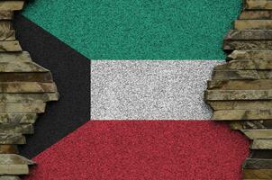 Kuwait flag depicted in paint colors on old stone wall closeup. Textured banner on rock wall background photo