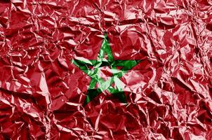 Morocco flag depicted in paint colors on shiny crumpled aluminium foil closeup. Textured banner on rough background photo