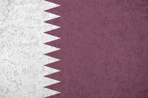 Qatar flag depicted in bright paint colors on old relief plastering wall. Textured banner on rough background photo