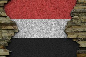 Yemen flag depicted in paint colors on old stone wall closeup. Textured banner on rock wall background photo