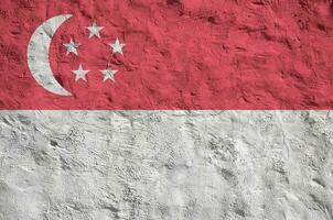 Singapore flag depicted in bright paint colors on old relief plastering wall. Textured banner on rough background photo