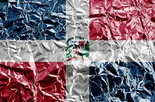 Dominican Republic flag depicted in paint colors on shiny crumpled aluminium foil closeup. Textured banner on rough background photo