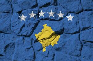 Kosovo flag depicted in paint colors on old stone wall closeup. Textured banner on rock wall background photo