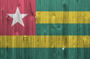 Togo flag depicted in bright paint colors on old wooden wall. Textured banner on rough background photo
