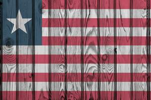 Liberia flag depicted in bright paint colors on old wooden wall. Textured banner on rough background photo