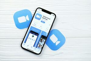KHARKOV, UKRAINE - MARCH 5, 2021 Zoom messenger icon and application from App store on iPhone 12 pro display screen on white table photo